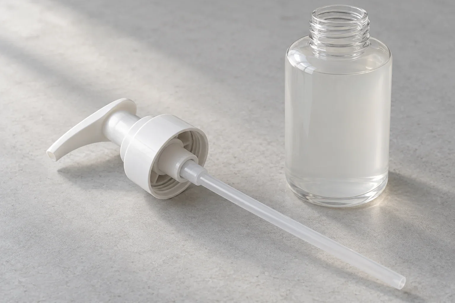 Separate pump collar and dip tube beside an open bottle
